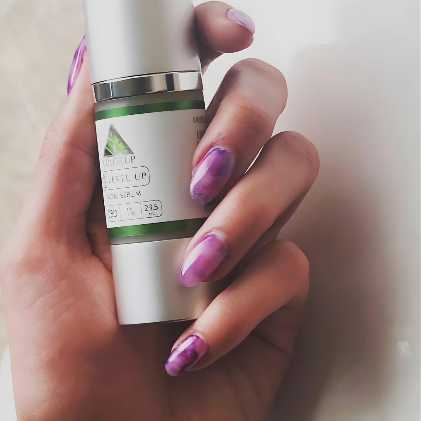 Hand holding a 'Color Up Level Up Serum' skincare bottle with purple fingernail polish