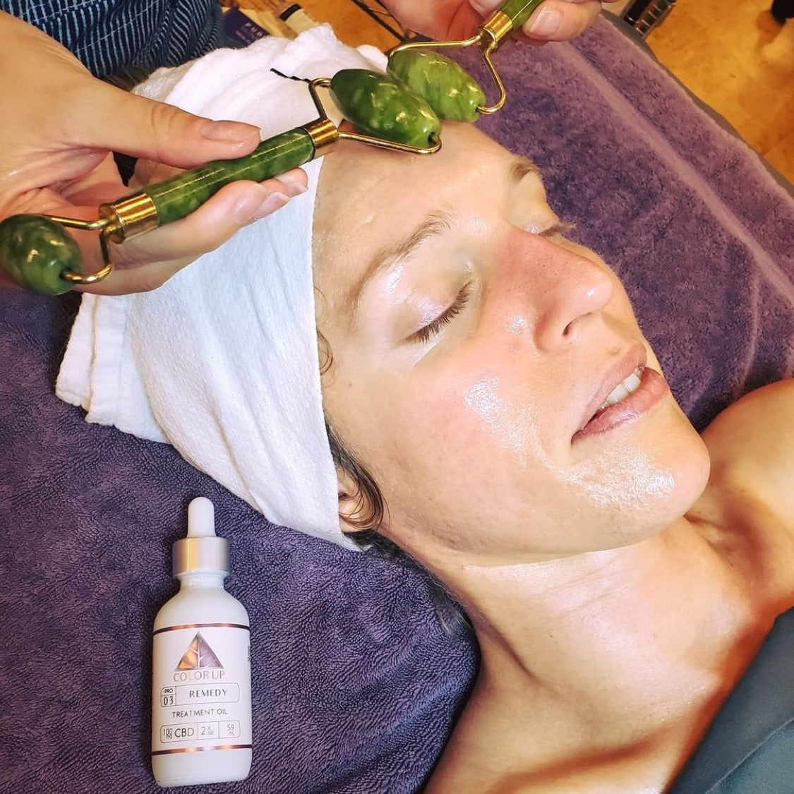 Esthetician performing a professional facial using Color Up Remedy Treatment Oil with jade rollers during a relaxing spa skincare treatment.
