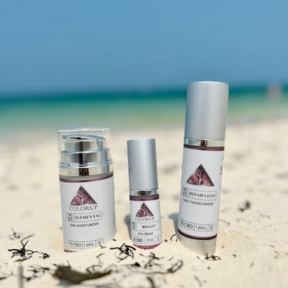 Color Up professional CBD skincare featuring Elemental Zinc Moisturizer, Bright Eye Cream, and Repair Light Daily Moisturizer on a beach.