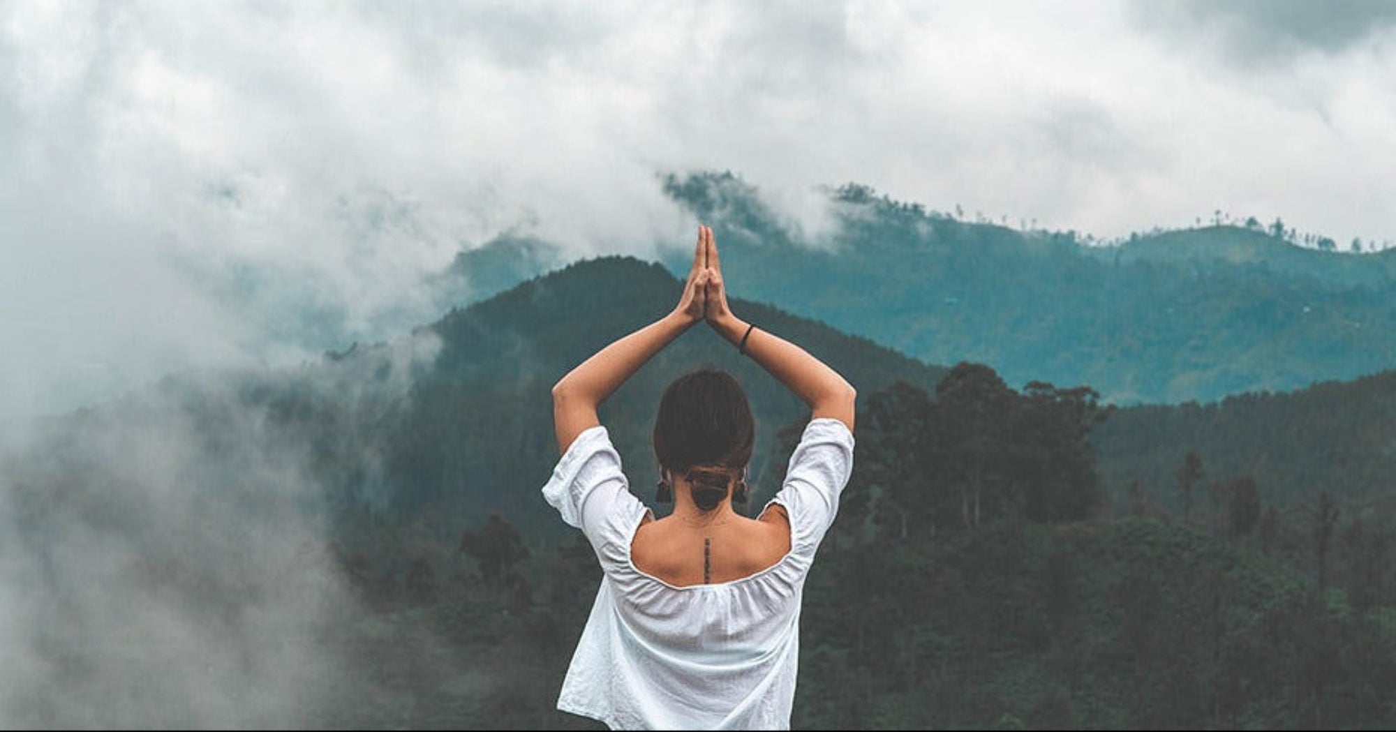 Person practicing mindfulness in the mountains representing holistic wellness, self-care, and the natural philosophy behind Color Up skincare.
