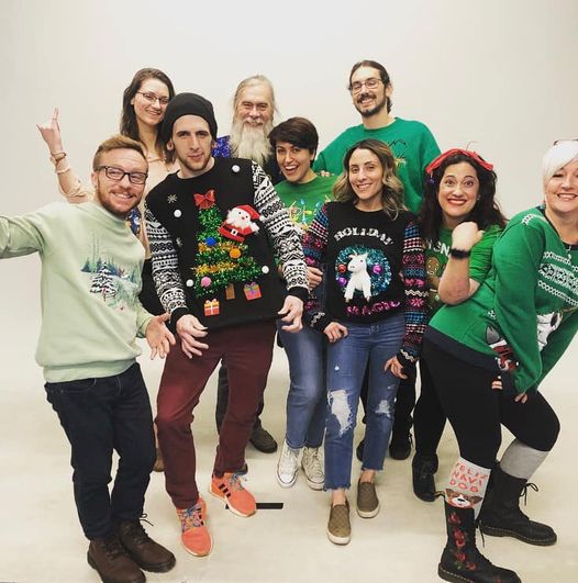 Group of people wearing festive sweaters posing together on a white background