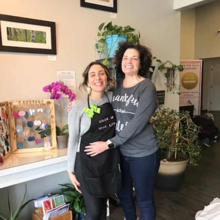 Two women standing together in a room with plants and decor - shauna and nicole color up cares day